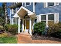 Inviting front entrance with a yellow door, brick pathway, and well-maintained landscaping at 201 Adams Way, Chapel Hill, NC 27516