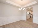 Light-filled dining room featuring wainscoting and a modern chandelier with luxury vinyl plank flooring at 316 Hopewell Branch Ct, Smithfield, NC 27577