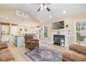 Bright, open-concept living space featuring a fireplace, modern ceiling fan, light wood flooring, and seamlessly connected kitchen at 35 Wickersham Way, Louisburg, NC 27549