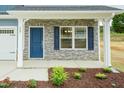 Charming home exterior featuring a blue front door, stone facade, and landscaped garden bed at 396 Hopewell Branch Ct, Smithfield, NC 27577