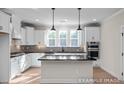 Modern kitchen featuring white cabinets, stainless steel appliances, a kitchen island with a dark countertop, and pendant lighting at 4825 Bristol Meadow Dr, Raleigh, NC 27603