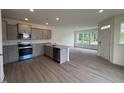 Open kitchen boasts gray cabinets, stainless appliances, and island with granite countertops overlooking the living area at 6401 Granite Quarry Dr, Raleigh, NC 27610