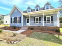 Inviting front porch with white railing, complemented by neat landscaping and brick accents at 117 Woodcroft Drive Dr, Angier, NC 27501