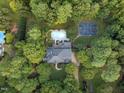Overhead view of a property with a pool and basketball court nestled amongst mature trees, offering privacy and recreation at 12012 Six Forks Rd, Raleigh, NC 27614