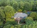 Aerial shot of a distinguished brick home surrounded by lush trees and landscaping, showcasing its private setting at 12012 Six Forks Rd, Raleigh, NC 27614