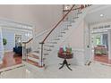 Elegant foyer showcasing a staircase with white spindles, wood railing and table with marble tiled floor at 12012 Six Forks Rd, Raleigh, NC 27614