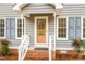 Close up view of a home's front door, white trim, and brick steps with a well-manicured lawn at 205 Fox Hollow Dr, Clayton, NC 27527