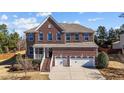 Stately brick home boasts a three-car garage and a well-manicured lawn at 705 Prince Dr, Holly Springs, NC 27540