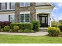 Close-up of a home's front entrance with a stone accent wall and well-maintained landscaping at 71 Del Corso Ct, Clayton, NC 27527