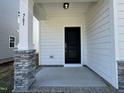 Inviting front porch with stone pillar accents, a black front door, and neutral siding at 761 Portland Rose Dr, Knightdale, NC 27545