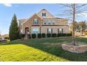 Beautiful two-story home boasts a brick and stone facade with lush landscaping on a sunny day at 78 Rolling Meadows Ln, Chapel Hill, NC 27517