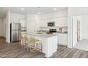 Bright kitchen featuring white cabinets, granite countertops, stainless steel appliances, and a kitchen island with barstool seating at 100 Big Dream Ct, Louisburg, NC 27549