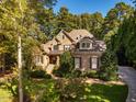 Elegant home showcasing a blend of stone and brick architecture with lush greenery at 1616 Kirkby Ln, Raleigh, NC 27614
