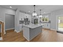 Modern kitchen with white cabinets, stainless steel appliances, large island, and pendant lighting at 163 Nashua Dr, Louisburg, NC 27549