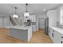 Modern kitchen with white cabinets, stainless steel appliances, large island, and hardwood floors at 163 Nashua Dr, Louisburg, NC 27549