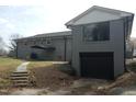 Two-story home showcasing a gray brick exterior, a black garage door, and a small backyard at 2602 Fayetteville St, Durham, NC 27707