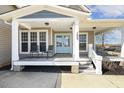 Inviting covered front porch with seating and a hanging porch swing, leads to a charming light blue double-door entrance at 288 Joseph Alexander Dr, Fuquay Varina, NC 27526