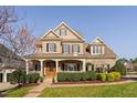 Beautifully landscaped brick home featuring a covered front porch and classic architectural details at 321 Weycroft Grant Dr, Cary, NC 27519