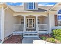 Inviting front porch with white railings and columns, leading to a glass-paneled front door and sidelight windows at 34 Triton Ct, Clayton, NC 27520