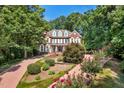 Beautiful brick home featuring a landscaped front yard with flowering bushes and a circular driveway, nestled among lush trees at 405 Silver Creek Trl, Chapel Hill, NC 27514