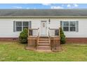 Close-up of a home's entrance with a small wooden porch and meticulously maintained landscaping at 4194 Abattoir Rd, Angier, NC 27501