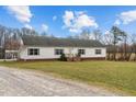 Exterior view of a one-story home with a gravel driveway and lush green lawn at 4194 Abattoir Rd, Angier, NC 27501