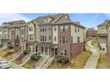 Street view of townhomes featuring brick and siding exteriors with manicured lawns at 556 Village Loop Dr, Apex, NC 27502