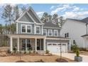 Charming two-story home boasts stylish gray siding, stone accents, a cozy porch with chairs, and a two-car garage at 724 Red Arrow Dr, Knightdale, NC 27545
