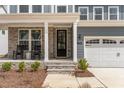 Inviting front porch with stone pillars, seating, and a stylish front door of a two-story house at 724 Red Arrow Dr, Knightdale, NC 27545