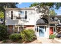 Charming townhouse featuring a blue front door with a black awning, complemented by lush greenery and mature trees at 7820 Falcon Rest Cir, Raleigh, NC 27615