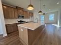 Spacious kitchen featuring wood cabinets, stainless appliances, island with white countertop and pendant lighting at 804 Hillfarm Dr, Wake Forest, NC 27587