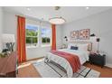 Well-lit bedroom with light gray walls, bright windows, a patterned rug, and orange drapes at 1028 Zelkova Ln, Chapel Hill, NC 27517
