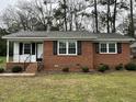 A closer view of the brick home with black shutters and nicely trimmed landscaping at 103 Beam Cir, Louisburg, NC 27549