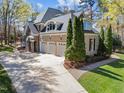 Large driveway leading to a three-car garage with well-maintained lawn and mature trees at 10540 Byrum Woods Dr, Raleigh, NC 27613