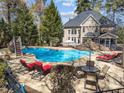 Inviting backyard pool area with lounge chairs, umbrella, and lush greenery at 10540 Byrum Woods Dr, Raleigh, NC 27613
