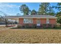 Charming brick home with mature landscaping featuring a covered parking area on a sunny day at 1101 Nashville Rd, Rocky Mount, NC 27803