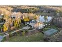 Sprawling estate with a tennis court, lush landscaping, and a serene pond surrounded by trees at 1404 Barony Lake Way, Raleigh, NC 27614