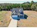 An aerial shot shows this home's location, nestled near a lush tree line, featuring an extended driveway and a well-kept lawn at 1613 Osprey Ridge Dr, Willow Springs, NC 27592
