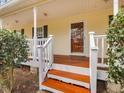 Inviting front porch with stained wood steps and white railing and yellow siding at 204 Sugarland Dr, Apex, NC 27502