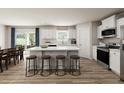 Modern kitchen with white cabinets, stainless steel appliances, and a large island with seating and wood floors at 27 Artesa Ct, Fuquay Varina, NC 27526