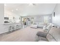 Bright, open-concept living room featuring plush carpet, comfortable seating, ceiling fan, and seamless flow to the kitchen at 31 Harrow Ter, Roxboro, NC 27574