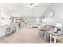 Bright, open-concept living room featuring plush carpet, comfortable seating, ceiling fan, and seamless flow to the kitchen at 31 Harrow Ter, Roxboro, NC 27574