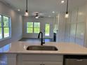 Modern kitchen view showcasing stainless steel appliances, a kitchen sink, and an open concept living space at 380 Pecan Valley Way, Four Oaks, NC 27524
