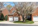 Classic two-story red brick home with a two-car garage surrounded by lush trees at 5036 Isabella Cannon Dr, Raleigh, NC 27612