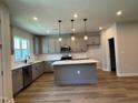 Modern kitchen boasts gray cabinetry, stainless steel appliances, a center island with white countertops, and stylish pendant lighting at 607 Callan View Ave, Wake Forest, NC 27587