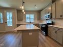 Modern kitchen boasts gray cabinetry, stainless steel appliances, a center island with white countertops, and stylish pendant lighting at 607 Callan View Ave, Wake Forest, NC 27587