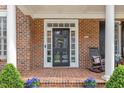 Close-up of a charming front porch with a decorative door, brickwork, and potted plants at 6116 Wilkinsburg Rd, Raleigh, NC 27612