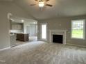 Open concept living area with fireplace, neutral carpet, and view into the kitchen at 103 Oakfield Trace Dr, Four Oaks, NC 27524