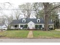 Charming two-story home with dormer windows, black shutters, brick walkway and mature landscaping at 105 John St, Louisburg, NC 27549
