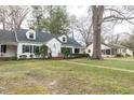 Charming two-story home with dormer windows, black shutters, brick walkway and mature landscaping at 105 John St, Louisburg, NC 27549